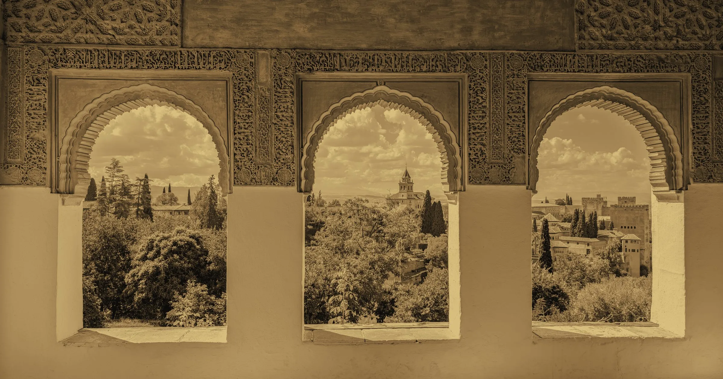 Three carved arches in the Alhambra, Granada, framing the hills beyond