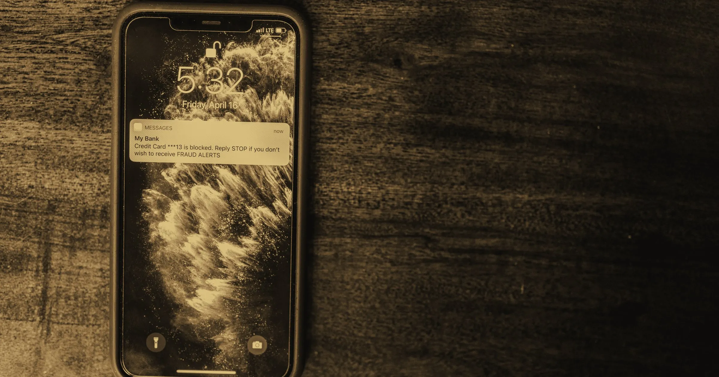 A smartphone lit up with a notification, lying on a dark wooden surface