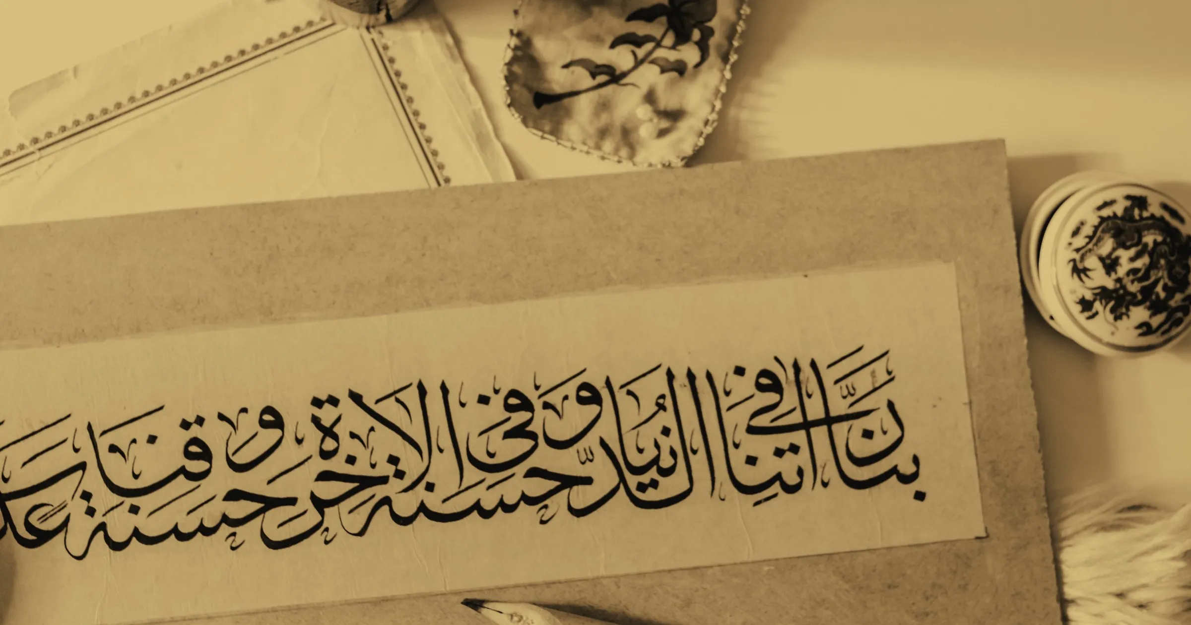 Arabic calligraphy written out in ink, with pens and an inkwell