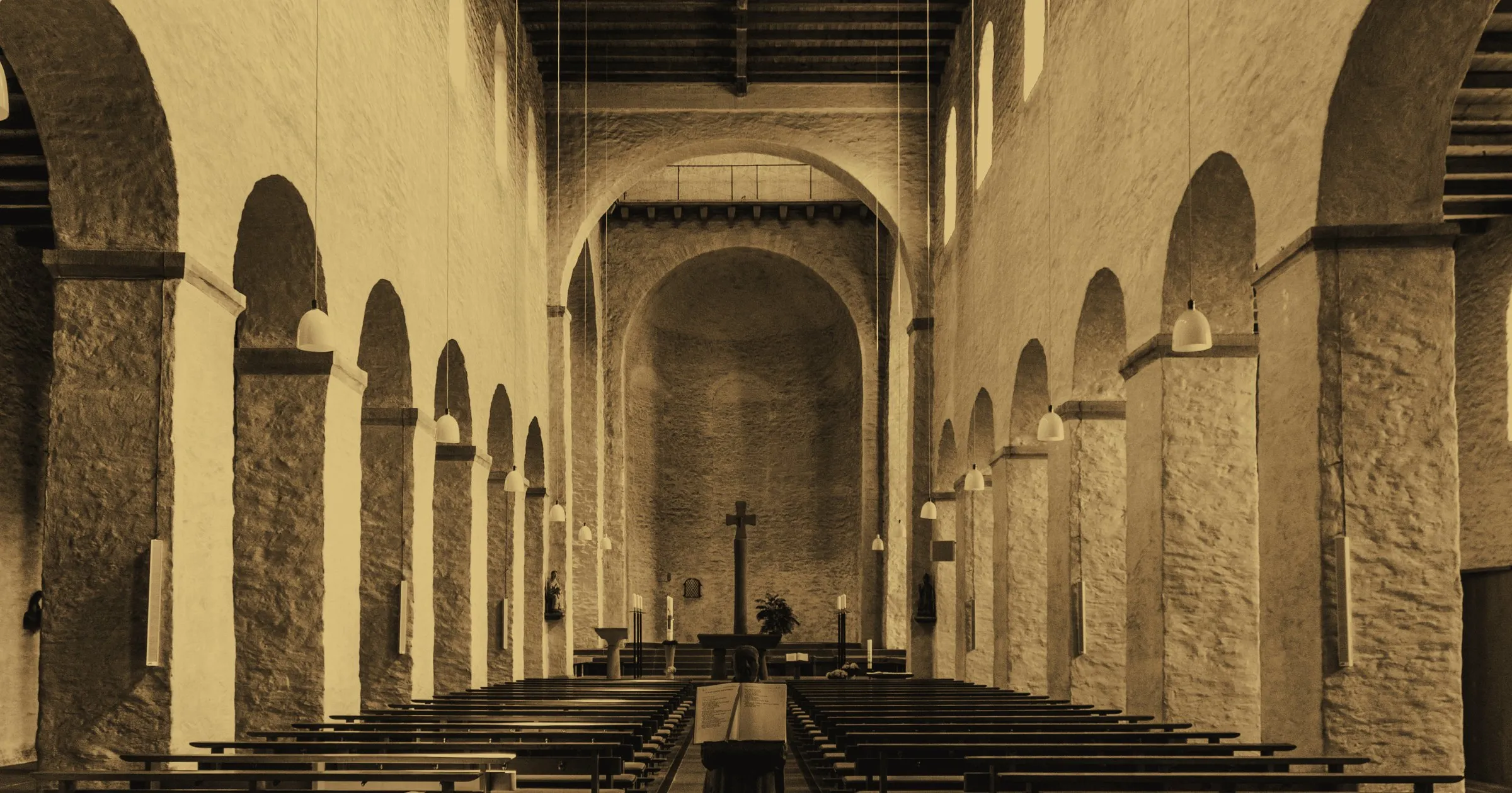 The empty nave of an old stone church, rows of pews facing the altar