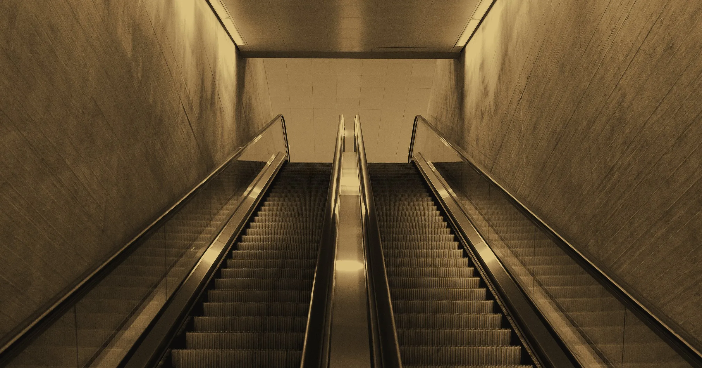 An empty escalator rising between two walls