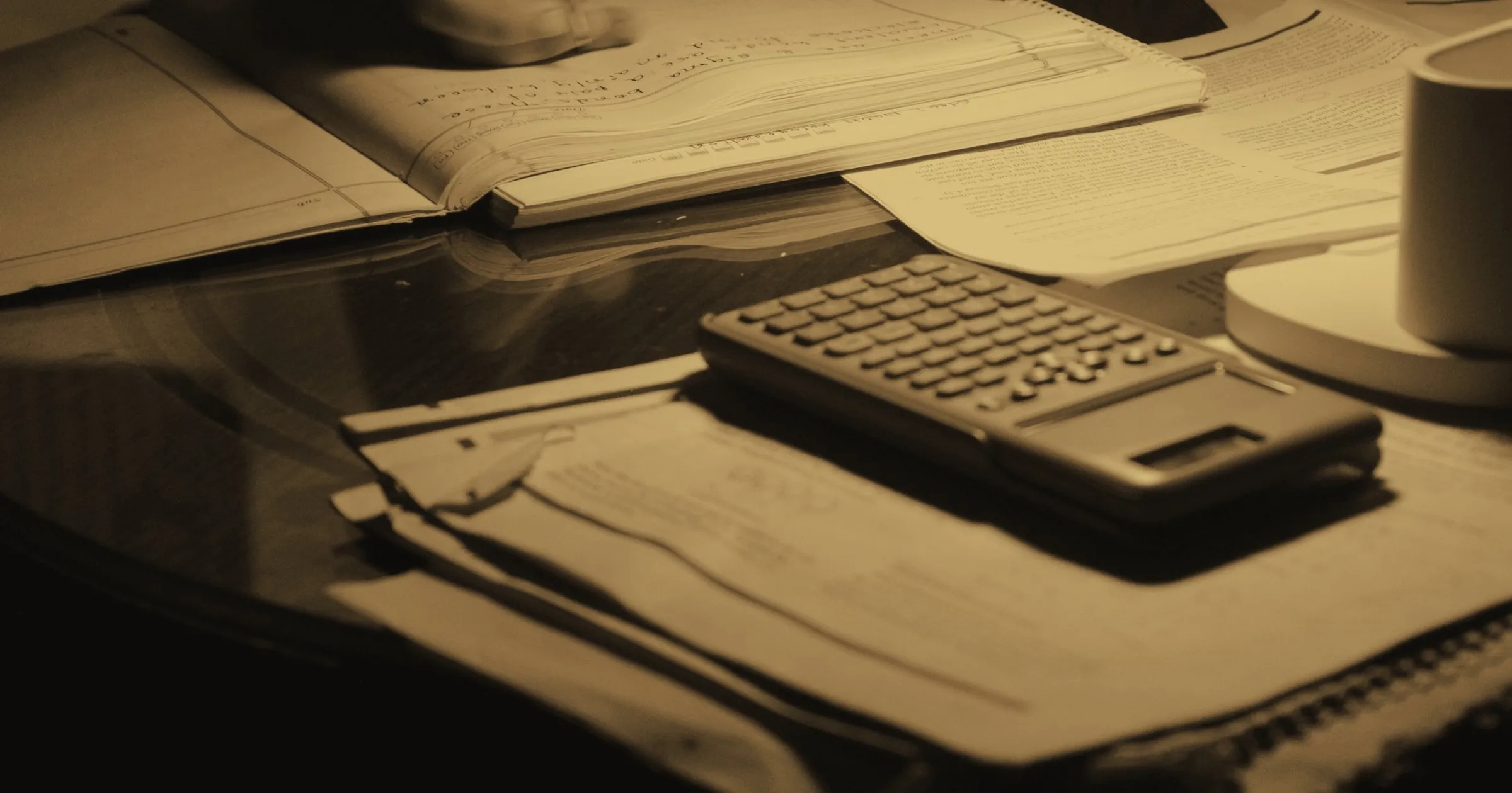 A calculator and papers on a desk late at night