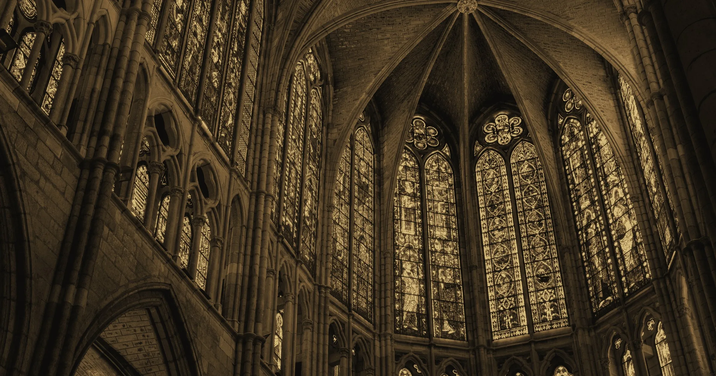 Tall stained-glass windows rising around the apse of a Gothic cathedral
