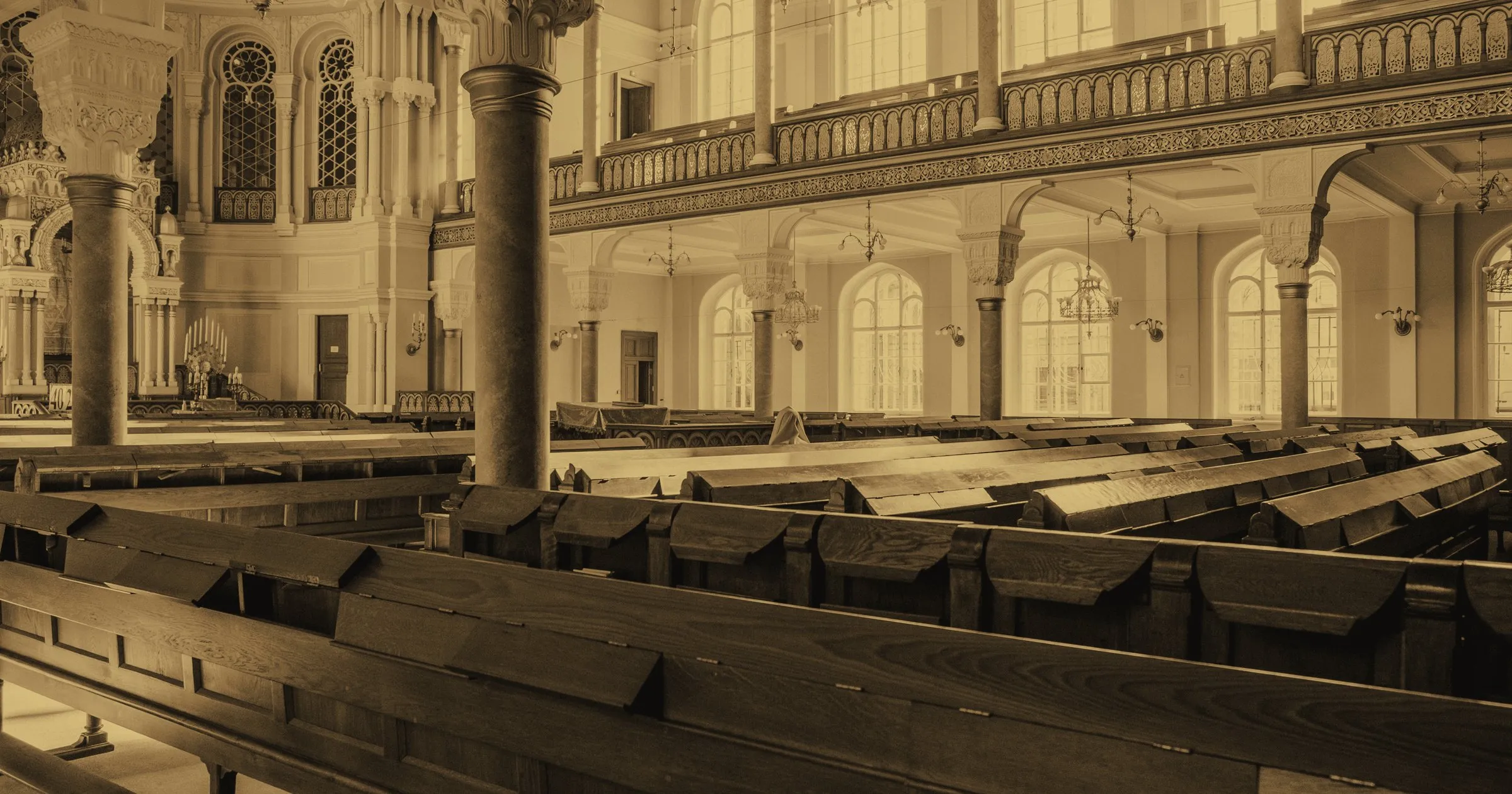 Empty wooden pews in the prayer hall of a large old synagogue