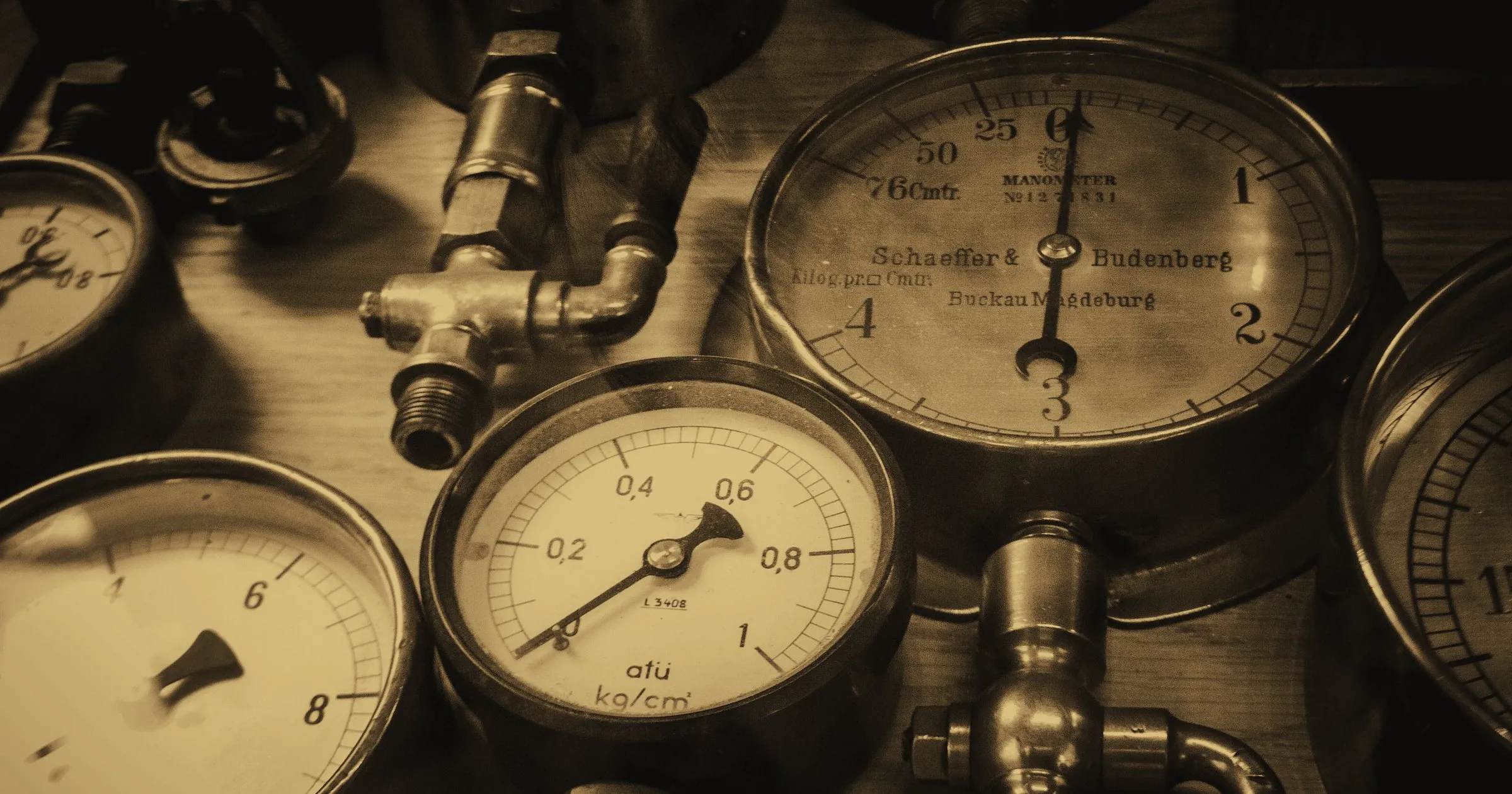 A cluster of old pressure gauges on industrial pipework