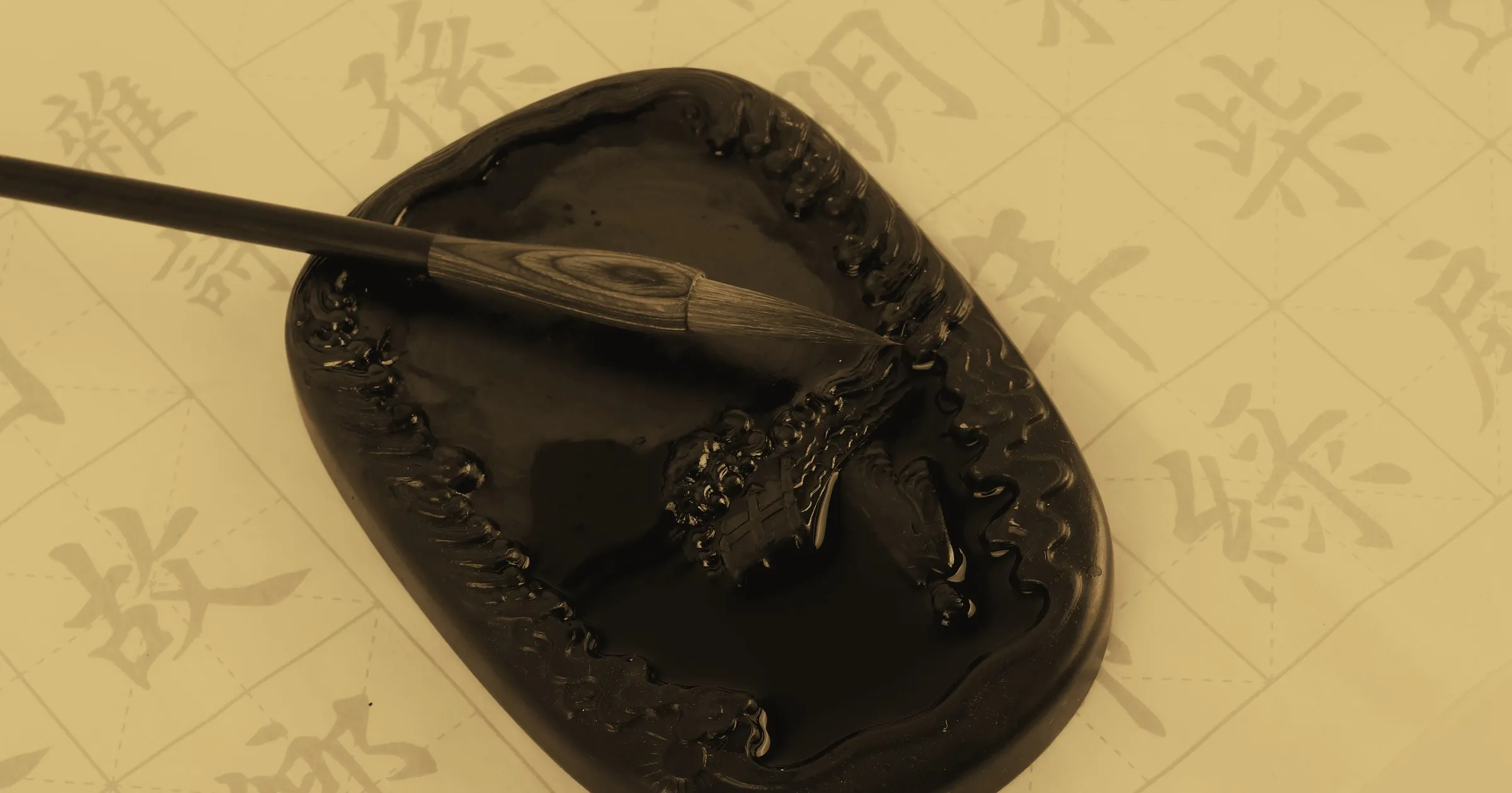 A calligraphy brush resting on an ink stone over sheets of Chinese characters