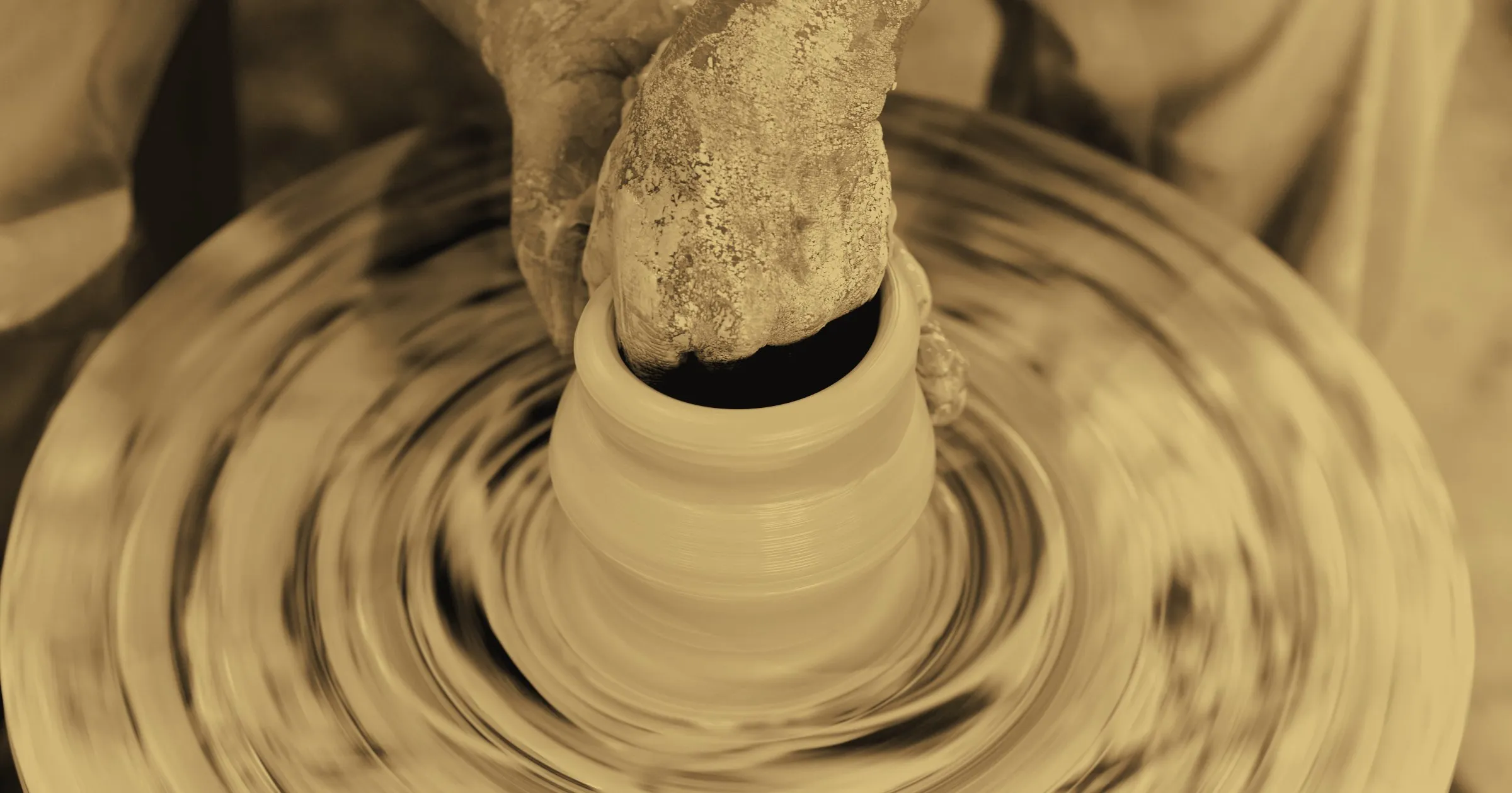 Hands shaping a clay pot on a potter's wheel