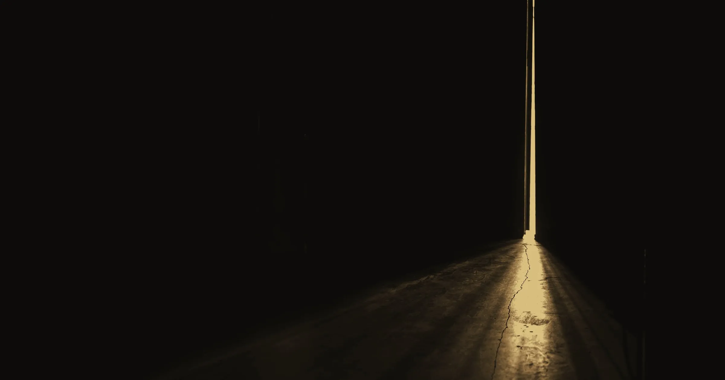 A narrow beam of light crossing a dark room from a door left ajar