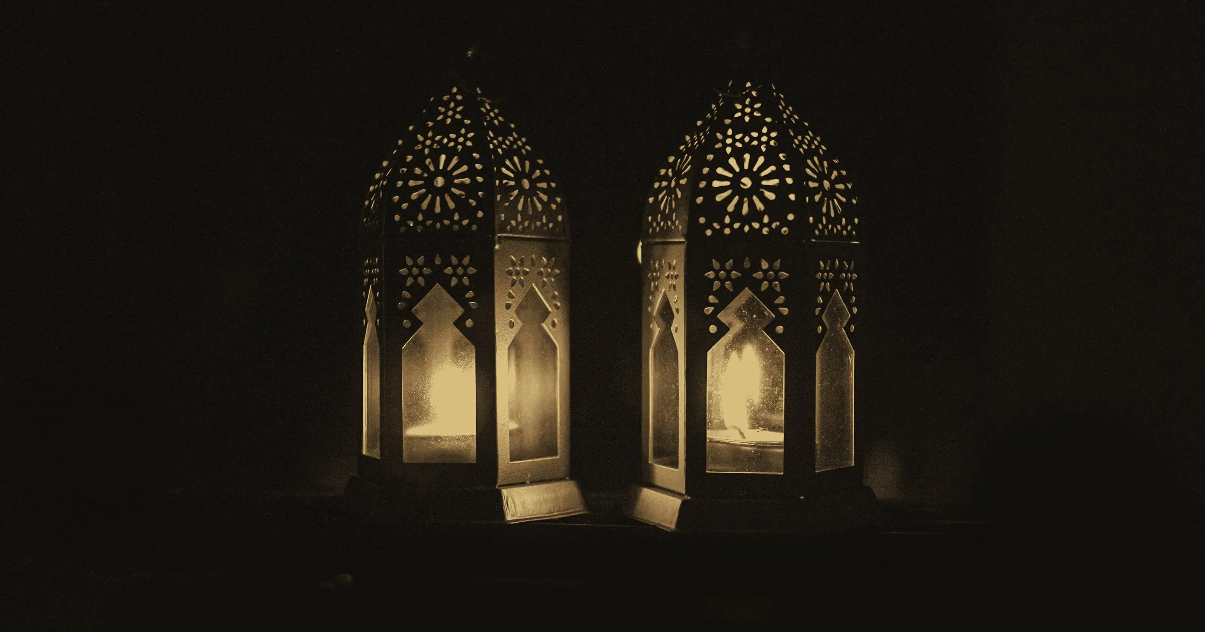 Two ornate lanterns glowing in the dark
