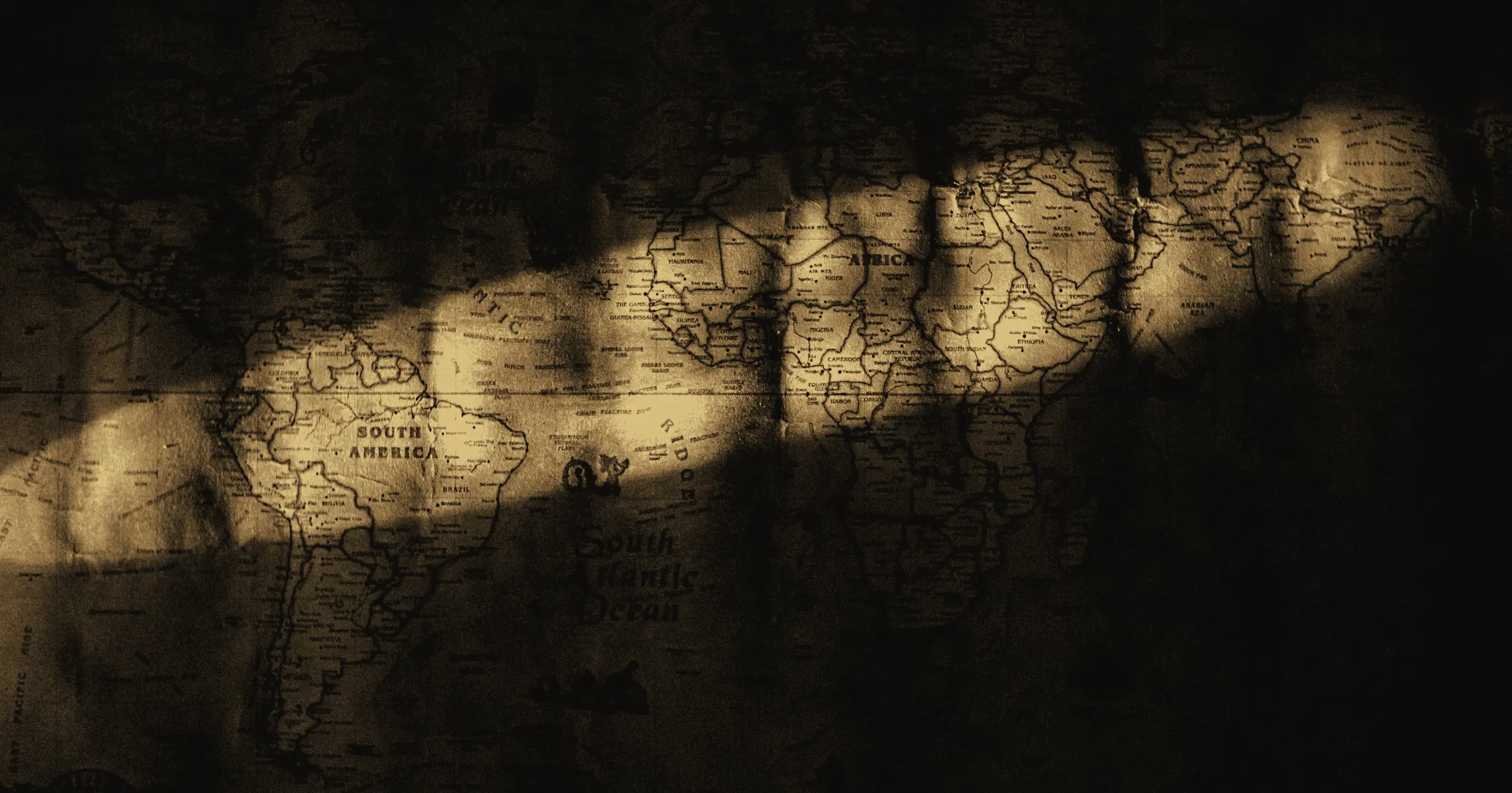 An old world map lying in bands of light and shadow