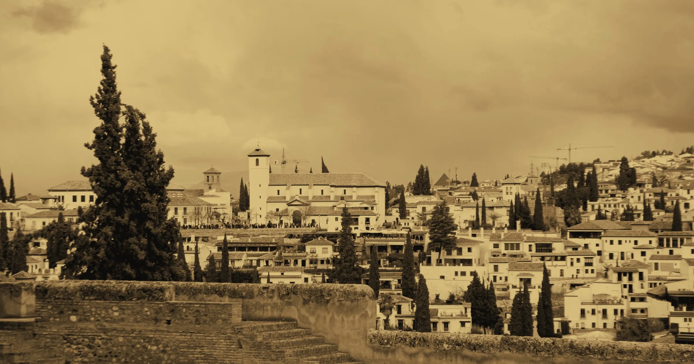 The white houses of the Albaicín in Granada, seen across a stone wall