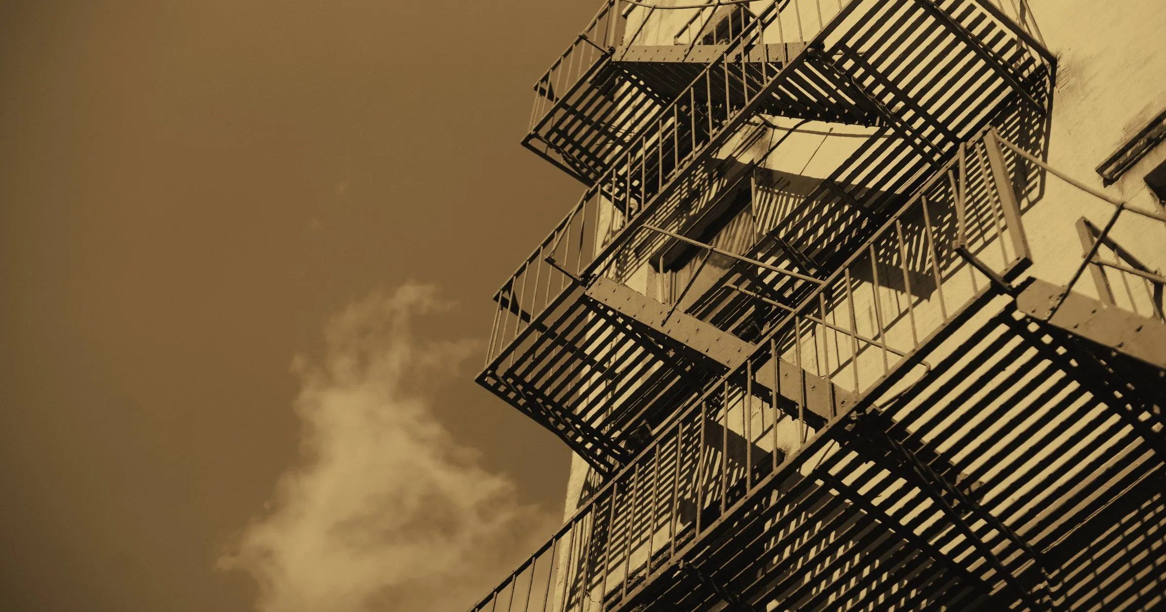 A metal fire escape climbing the side of a building against the sky