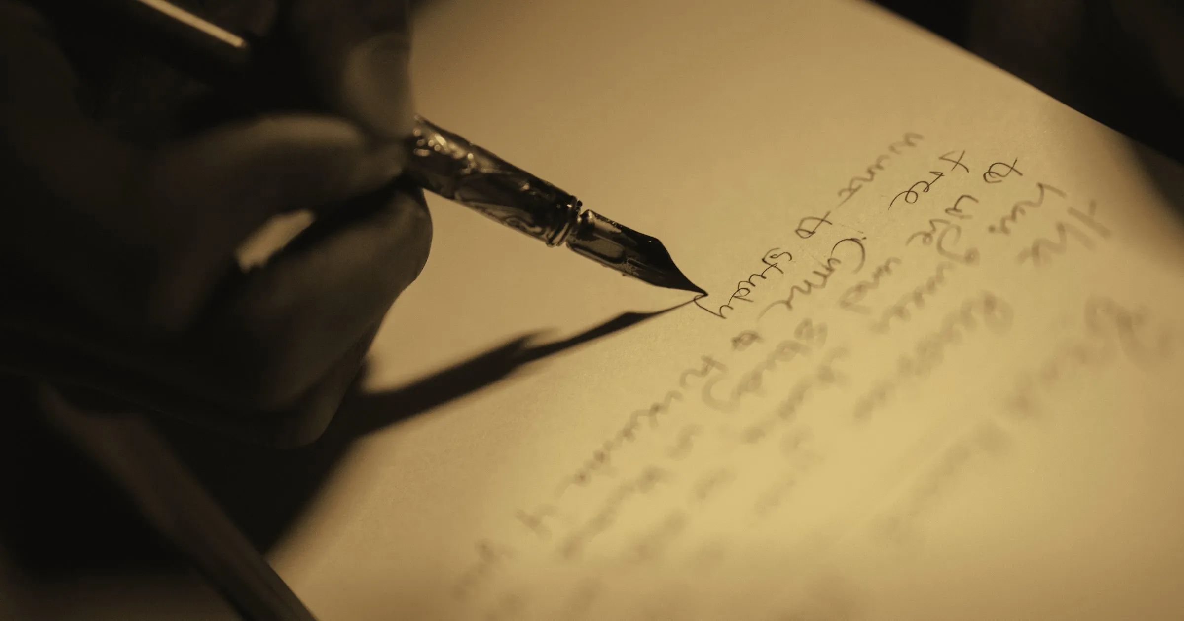 A hand writing a letter with a fountain pen